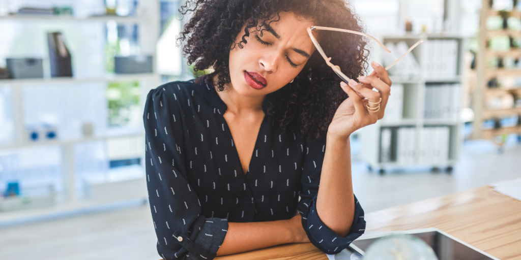 Cropped shot of an attractive young businesswoman sitting alone in her office and suffering from a headache