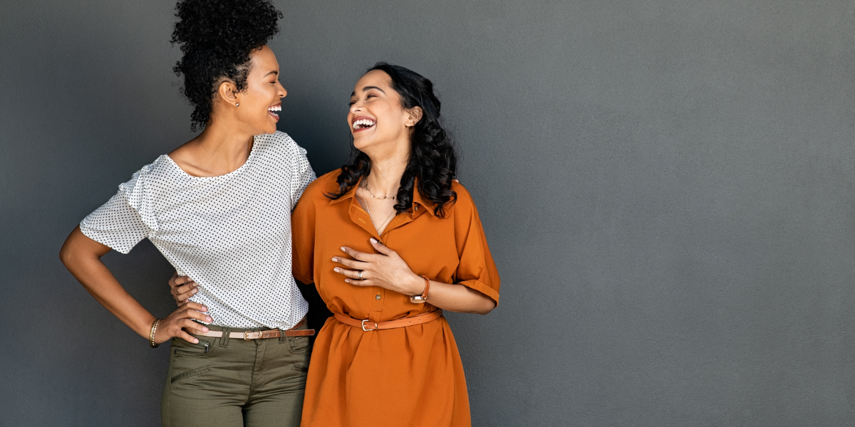 Happy smiling multiethnic women embracing each other against grey wall with copy space
